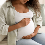 A woman holds her pregnant belly in serene neutral background
